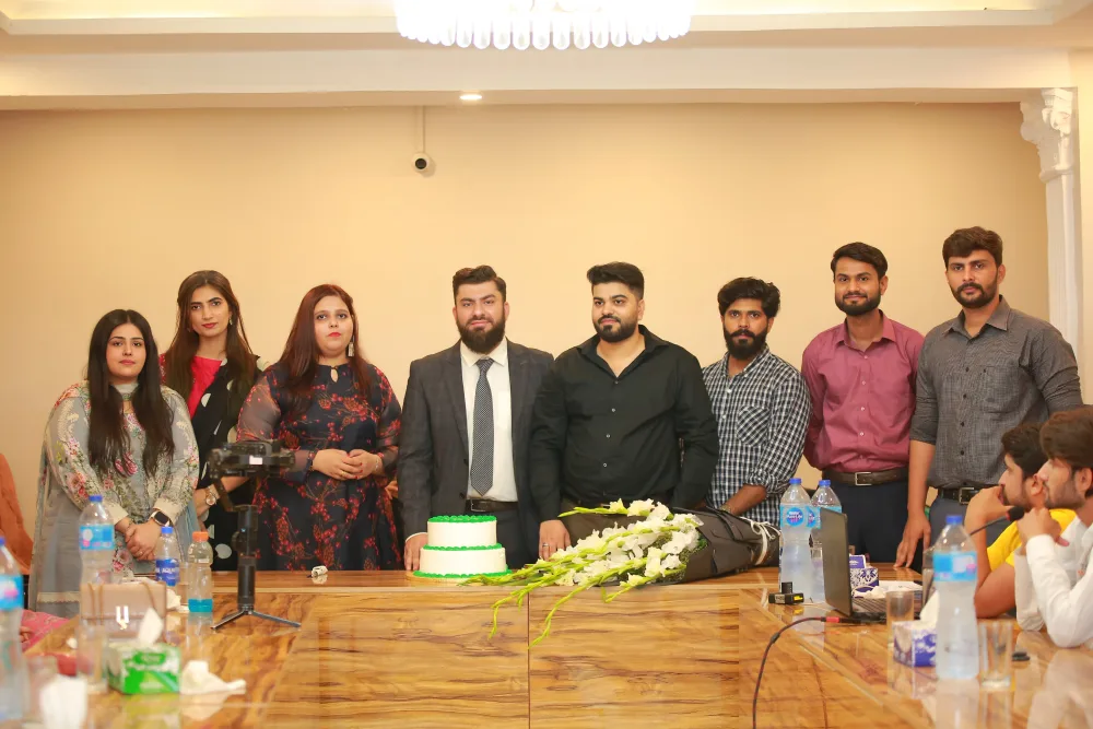 WeProms colleagues standing together around a celebration cake and flowers.