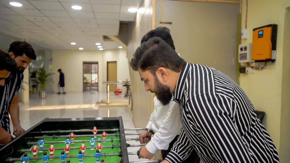 WeProms colleagues playing table football in the office