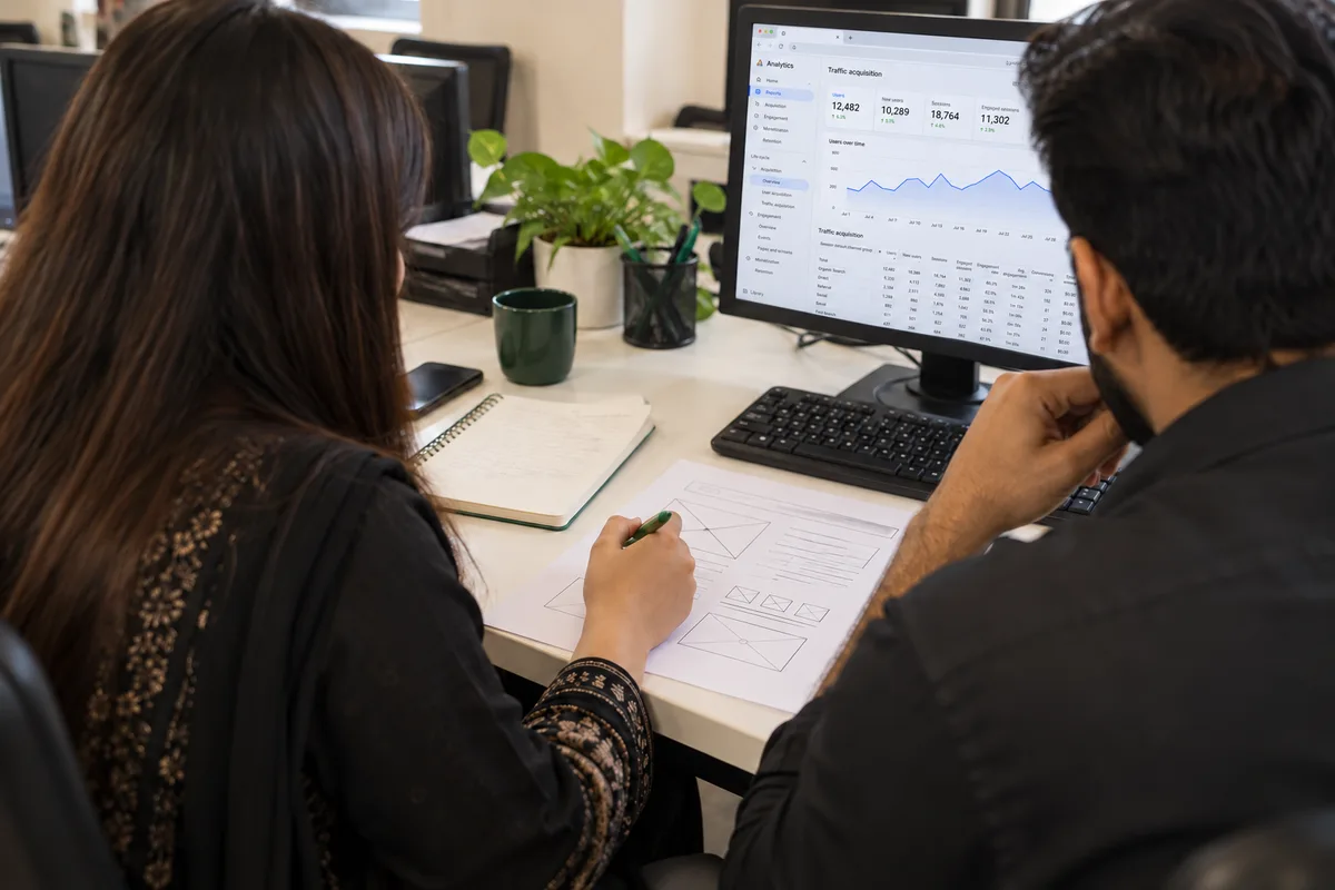 AI-created visualisation of two colleagues reviewing browser analytics at a shared desk, inspired by the Lahore office